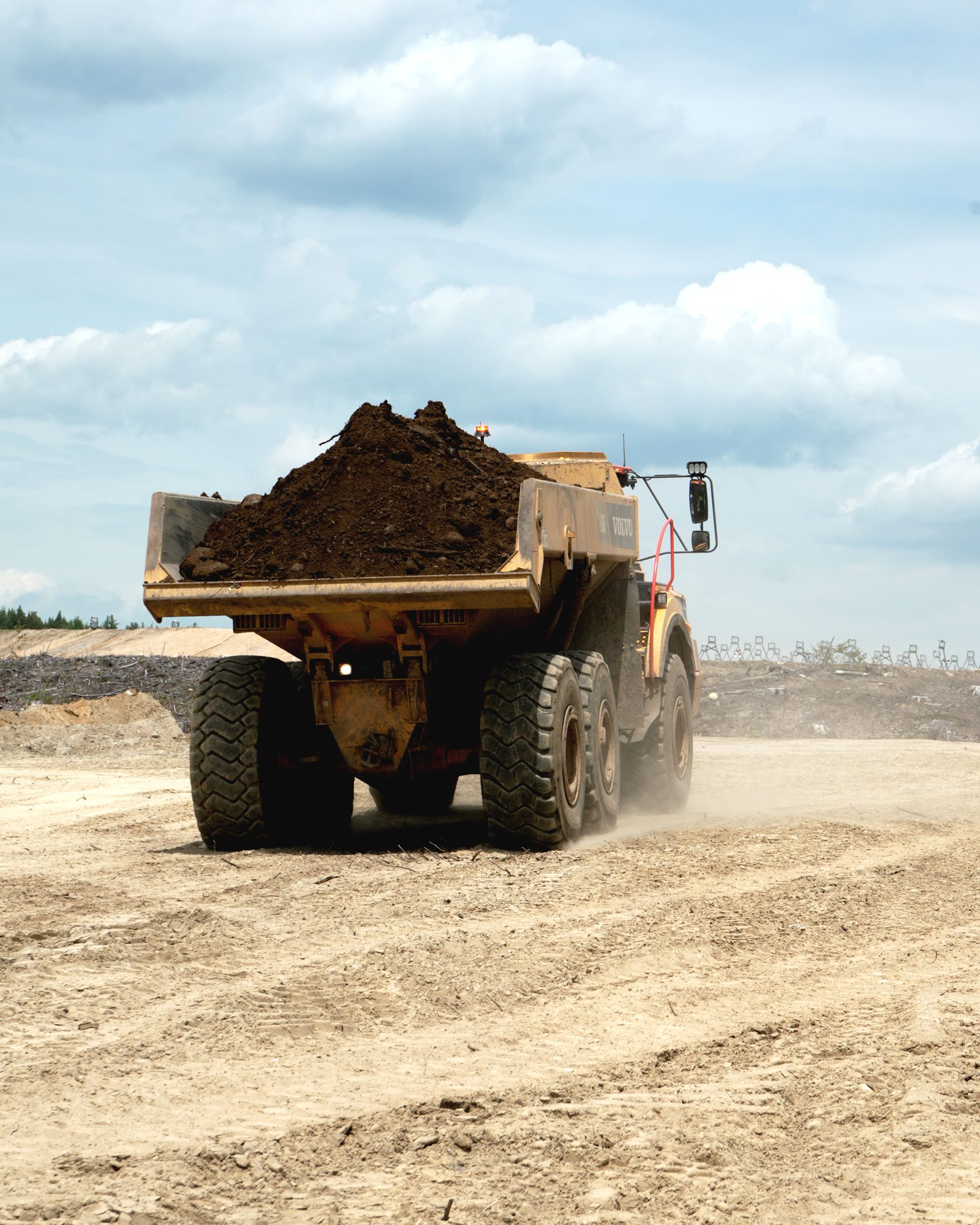 A loaded articulated haul truck carrying earth away from a working face.